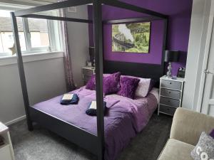 a bedroom with a canopy bed with purple sheets at Gadsby manor in Drumchapel