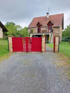 un cancello rosso davanti a una casa di Maison à la campagne a Beyssac