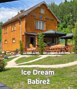 una casa di tronchi con un tavolo e sedie di fronte di STD Ice Dream 