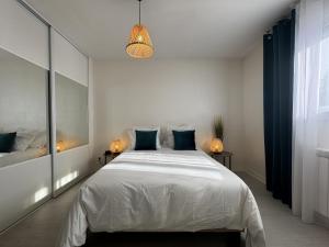 a bedroom with a large white bed with blue pillows at le Villaret - 4pers - Climatisation - Rêve au Mans in Coulaines