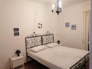 a bedroom with a bed with white sheets and a chandelier at La Casa Blu a Montalto Marina in Torre di Montalto