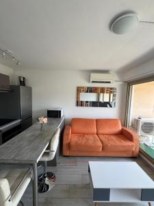 罗克布吕讷-卡普马丹Studio ideal pour les vacances的客厅里有一张橙色的沙发和一张桌子。 更多14张照片