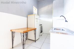 a kitchen with a white refrigerator and a wooden table at Hostel Mineirinho in Belo Horizonte +22 photos