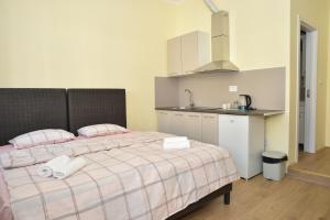 a bedroom with a bed with two pillows and a kitchen at mir rooms and apartments in Belgrade