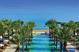 ein Resort mit Palmen und dem Meer im Hintergrund in der Unterkunft Al Bustan Palace, a Ritz-Carlton Hotel in Muscat