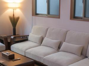 ein Wohnzimmer mit einer weißen Couch und einem Tisch in der Unterkunft GOHO STAY me Sumiyoshi in Tokio