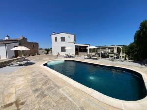 a swimming pool in front of a house at Agriturismo Masseria Saittole in Carpignano Salentino