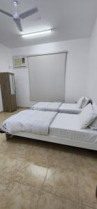 a large white bed in a white room at Hasik Beachfront Apartments in Ḩaḑbaram