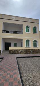 a large building with green windows and a brick driveway at Hasik Beachfront Apartments in Ḩaḑbaram