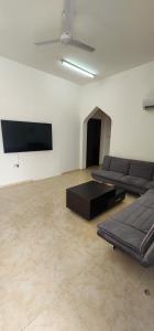 a living room with couches and a flat screen tv at Hasik Beachfront Apartments in Ḩaḑbaram