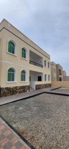 a large building with green windows and a driveway at Hasik Beachfront Apartments in Ḩaḑbaram