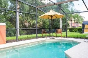 a pool with an umbrella and two chairs and a table with an umbrella at Spectacular House with 3BR - Private Pool, BBQ - Minutes from Disney! in Kissimmee +75 photos