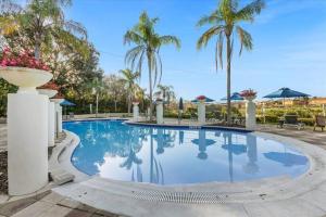 a large swimming pool with palm trees in the background at Spectacular House with 3 BR - Private Pool, BBQ - Minutes from Disney! in Kissimmee +76 photos
