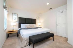 a bedroom with a large white bed and a stool at Spectacular House with 3 BR - Private Pool, BBQ - Minutes from Disney! in Kissimmee +75 photos