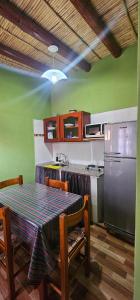 a kitchen with a table with chairs and a refrigerator at Cabaña KUYAY in Purmamarca