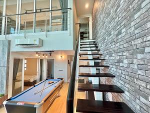 a staircase with a pool table and a brick wall at Maritime Suite #Full Seaview with sunrise #Pool Table #Water filter machine #Georgetown #6pax duplex unit #Private host in Jelutong