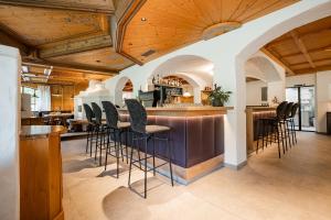 a bar with stools in a kitchen with wooden ceilings at Hotel Dorfer in Grossarl