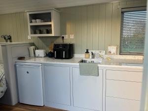 a kitchen with white cabinets and a sink at Oyster Bay Retreats in Balnacart