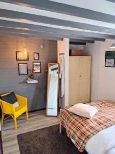 a bedroom with a bed and a mirror and a yellow chair at Milking Shed Cottage in Narberth