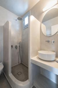 a bathroom with a shower and a sink and a mirror at Akrotiri Hotel in Akrotiri
