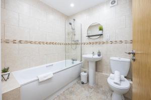a bathroom with a toilet and a tub and a sink at Stylish 2-Bed Apartment in Manchester City Centre in Manchester