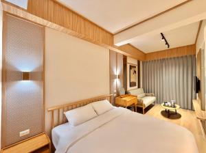 Un dormitorio con una gran cama blanca y una silla. en Choozme, en Lukang