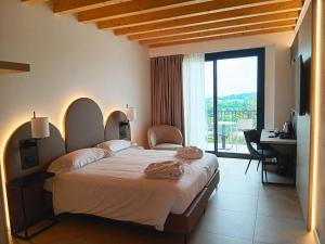 a bedroom with a large bed with a desk and a window at Villa Luisa Resort & Luxury Apartments in San Felice del Benaco