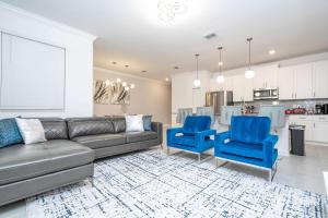 a living room with a couch and two blue chairs at Stylish 4BR Resort Home with Private Pool & Fun Themed Rooms Near Disney in Kissimmee