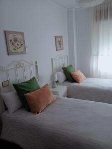 una camera con 2 letti con cuscini verdi e bianchi di Apartamento en Cee a Cee