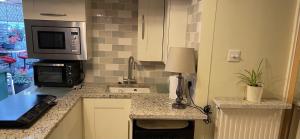 a kitchen with a counter top with a microwave at STAPLEHURST COTTAGE in Sandgate +12 photos