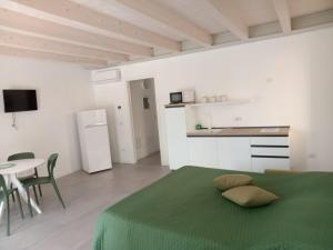 a white room with a green bed and a table at Le Casette QUATTRO in Pacengo di Lazise