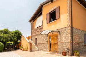 a yellow building with a wooden door and stairs at B&B Casale Ansamagi Relax & Pool in Genzano di Roma
