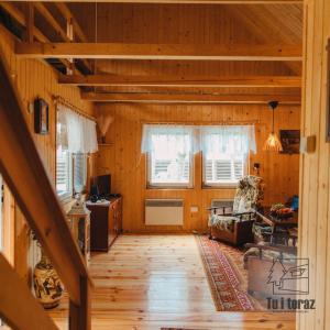 a living room with wooden walls and wooden floors at Tu i teraz- Domek wypoczynkowy in Kamienica Królewska