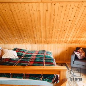 a bed in a room with a wooden wall at Tu i teraz- Domek wypoczynkowy in Kamienica Królewska