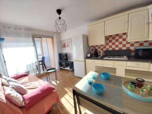 a kitchen and living room with a couch and a table at T2, wifi et parking, 4 couchages, centre station in Narbonne-Plage