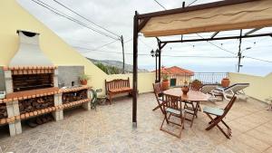 Un patio con mesa y sillas y una chimenea. en Escada Villa, en Bicas