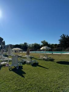 a group of lounge chairs and umbrellas on the grass at Casa Numana Adamo ed Eva resort in Numana +10 photos