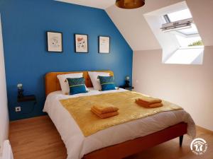 a bedroom with a large bed with a blue wall at Le Logis des Vallées, 6/7 pers avec piscine et sauna in Ambrieres Les Vallees