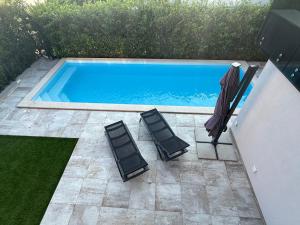 two chairs and an umbrella next to a swimming pool at Apartmen ARMINAN 52 TERRACE, POOL FREE PARKING -NOVIGRAD in Novigrad Istria