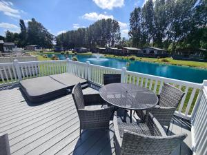 eine Terrasse mit Tisch und Stühlen und einem Tisch und einem Pool in der Unterkunft Honey Bee Lodge With Hot Tub in York