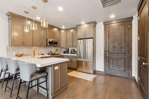 a kitchen with wooden cabinets and a kitchen island with bar stools at Modern Mountain Escape at Blackstone Walk to the Slopes in Park City