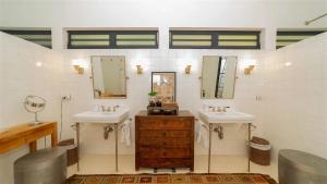 ein Badezimmer mit zwei Waschbecken und zwei Spiegeln in der Unterkunft Utmost Luxury In The Heart Of Tropical Nature in Marigot