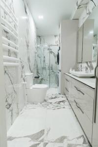 a white bathroom with a shower and a toilet at Luxury 2- Bedroom with Balcony in Prime Location in Chişinău
