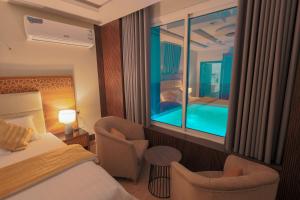 a hotel room with a bed and chairs and a window at منتجع و شاليهات المخمل Velvet Chalets and resort in Taif +49 photos