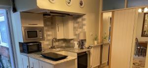 a small kitchen with a sink and a microwave at STAPLEHURST COTTAGE in Sandgate