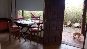 a dining room with a table and a dog looking out the door at El Quebrachal Del Monte in Capilla del Monte