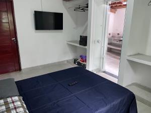 a bedroom with a blue bed and a tv on the wall at Casa na mata in Ilhabela