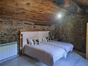 two beds in a room with a stone wall at Casa Dos Avós - Alojamento Local in Bragança