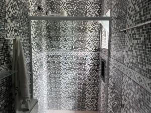 a bathroom with a shower with black and white tiles at Casa na mata in Ilhabela