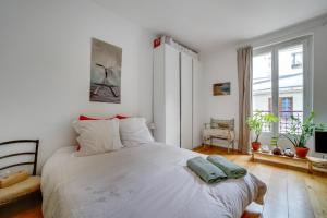 ein Schlafzimmer mit einem weißen Bett und einem Fenster in der Unterkunft Appartement Romantique à Saint-Ouen in Saint-Ouen